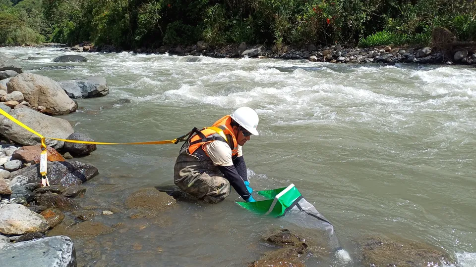 Técnico muestreando agua en un río de montaña