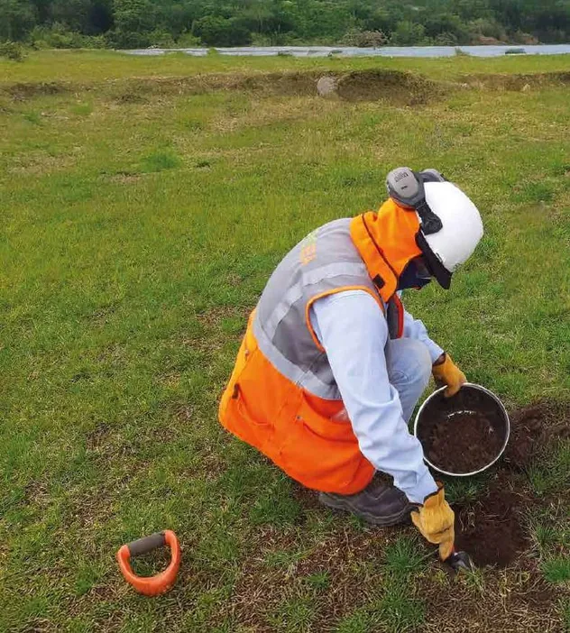 Técnico con equipo de protección tomando una muestra de suelo